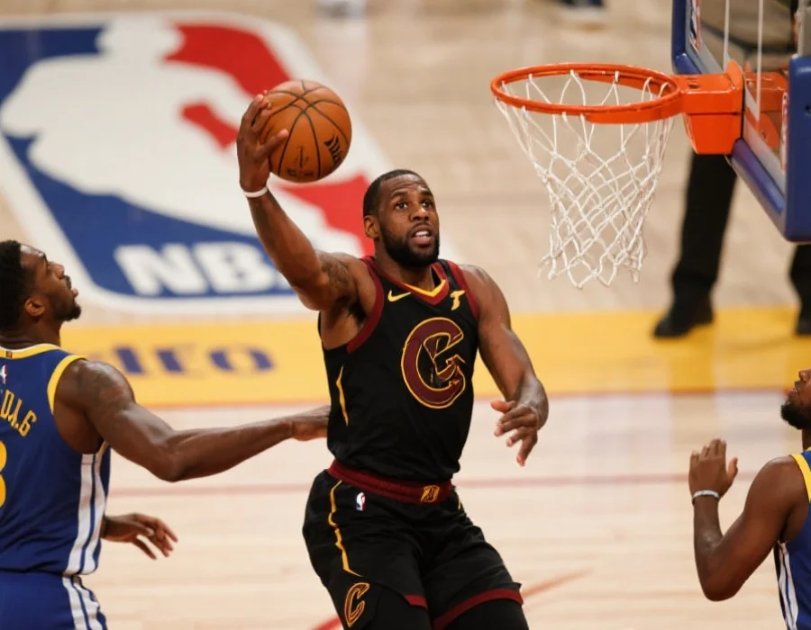 一名NBA明星球员在总决赛中突破防守队员准备扣篮，聚焦于球员的力量与专注